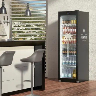 Schwarzer Getränkekühlschrank mit individuell bedrucktem Gehäuse, gefüllt mit Getränken, neben moderner Bar und Hockern.