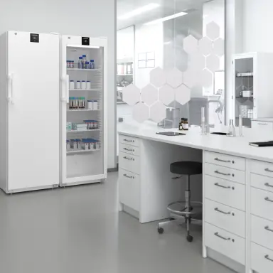 Laborkühlgeräte für Probenlagerung Zwei weisse Laborkühlgeräte in modernem Labor, eines mit Glastür und gelagerten Probenbehältern.