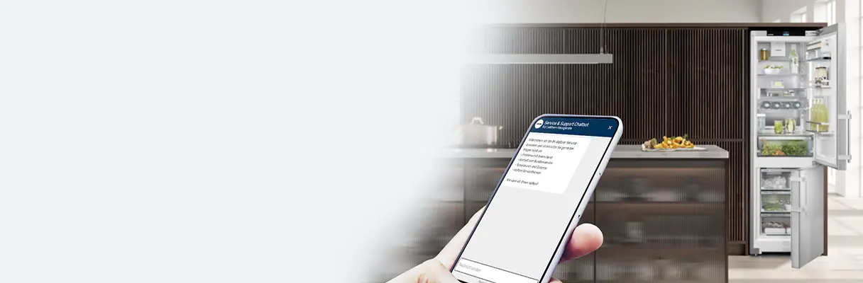 Hand hält Smartphone mit geöffnetem Chatbot vor moderner Küche mit offenem Kühlschrank Hand hält Smartphone mit geöffnetem Chatbot vor moderner Küche mit offenem Kühlschrank