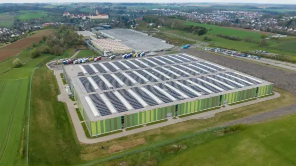 The Factory Ochsenhausen logistics center is prominently featured, showcasing its modern architecture and extensive photovoltaic panels on the roof.
