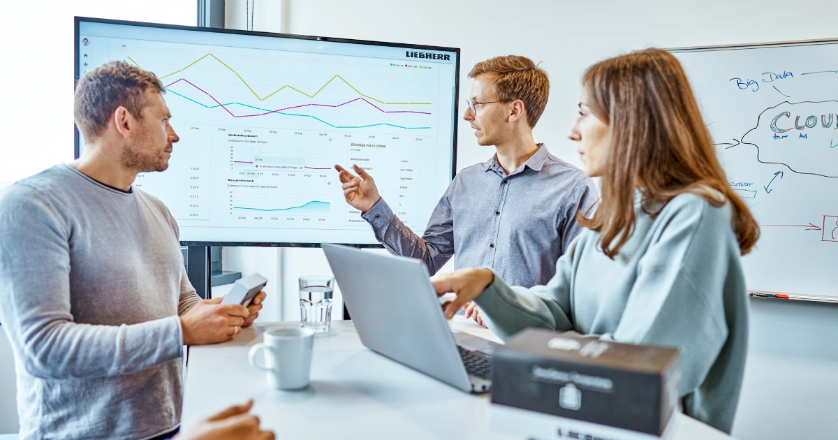 Group of professionals discussing in front of a big screen A diverse group of professionals engaged in a lively discussion, gathered around a large screen displaying important information