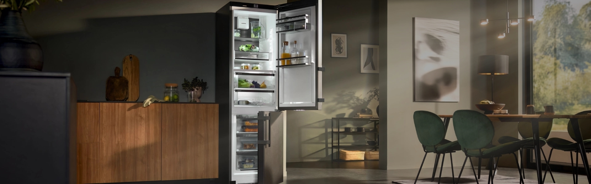 CBNbsa575 fridge freezer in a modern kitchen The CBNbsa575 fridge freezer stands elegantly in a modern kitchen, illuminated by soft sunrays filtering through the windows. The moody ambiance enhances the sleek design of the kitchen and dining area.