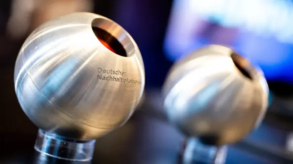 Deutscher Nachhaltigkeitspreis Trophäen des Deutschen Nachhaltigkeitspreises in metallischer Kugelform auf transparenten Sockeln.