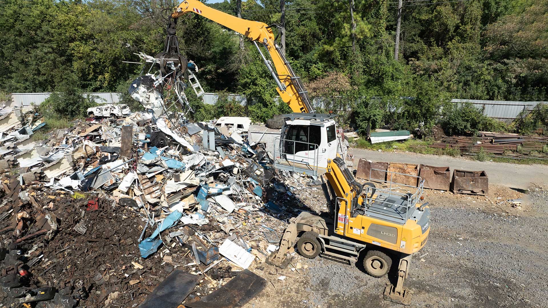 Scrap yard scene with Liebherr machines loading recycled metals for transport to domestic and international markets.