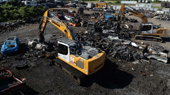Liebherr LH 30 M material handler sorting large car frames and heavy melting steel at recycling site.