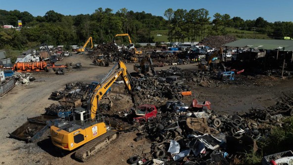 Close-up of Liebherr excavator equipped with hydraulic magnet lifting ferrous scrap metal.