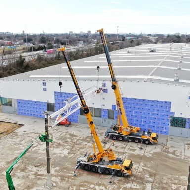 Prillaman Crane and Rigging utilizing a yellow Liebherr LTM 1090-4.2  mobile crane and a LTM 1250-5.1 mobile crane to complete a safe demolition at the back of the Liebherr Mining Newport News campus.