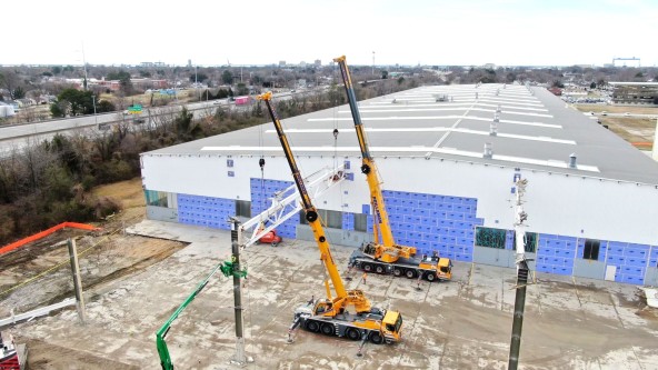 Prillaman Crane and Rigging utilizing a yellow Liebherr LTM 1090-4.2  mobile crane and a LTM 1250-5.1 mobile crane to complete a safe demolition at the back of the Liebherr Mining Newport News campus.