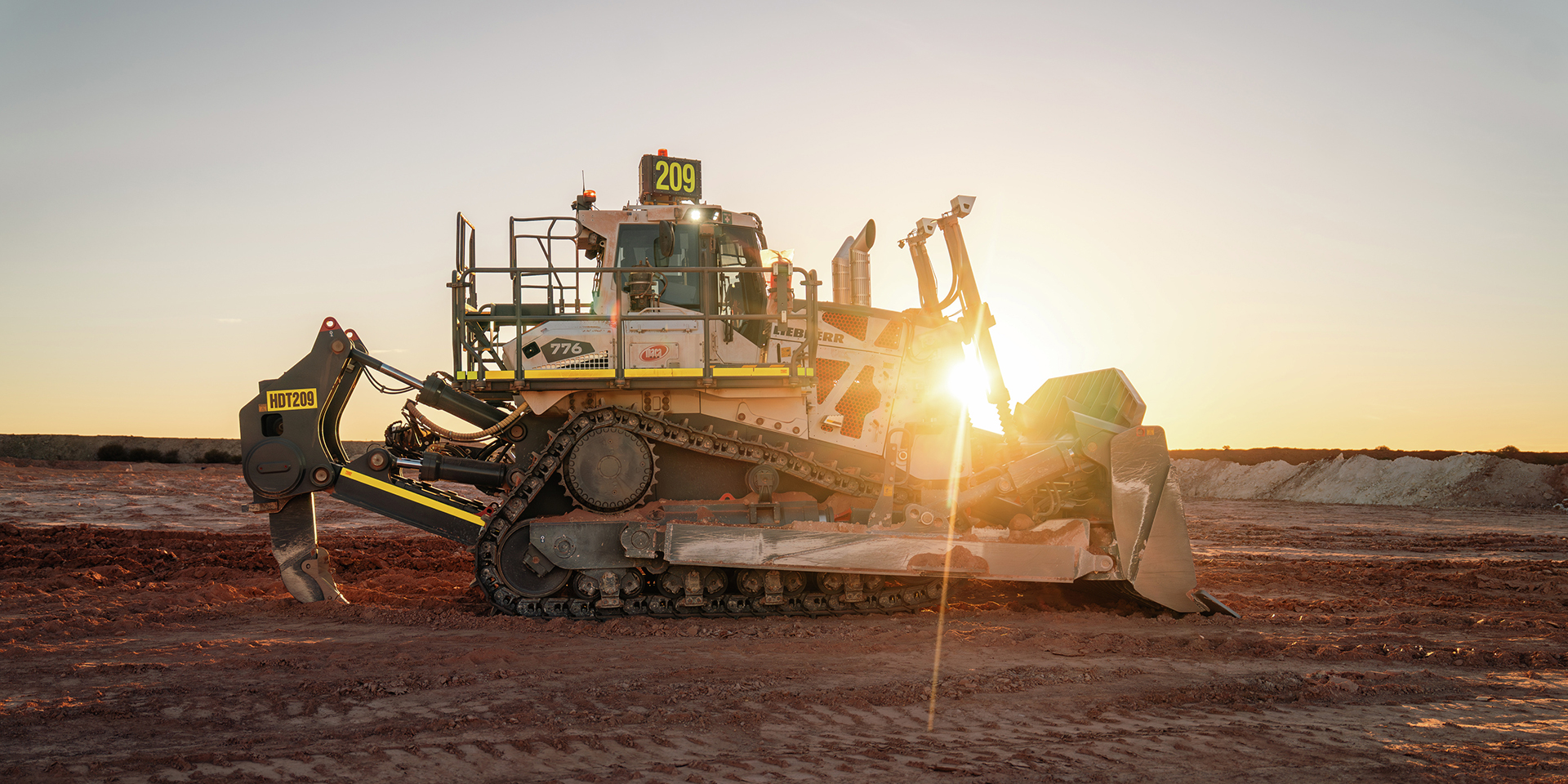 Liebherr PR 776 hydrostatic mining dozer Liebherr PR 776 mining dozer shown in profile against the setting sun at a rugged mine site.