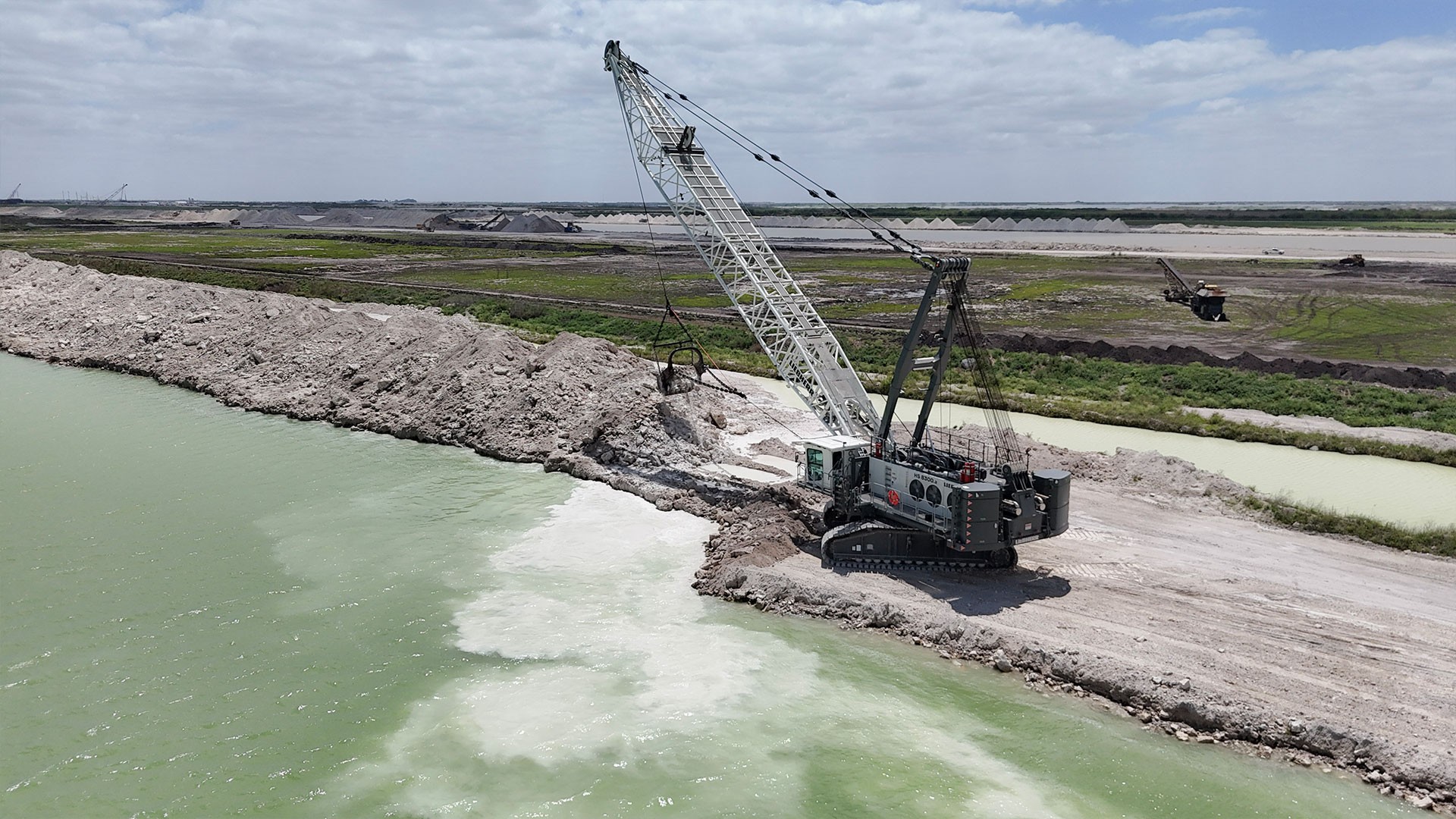 Aerial view of Liebherr HS 8300.2 dragline excavating material along water edge in quarry Aerial view of Liebherr HS 8300.2 dragline excavating material along water edge in quarry