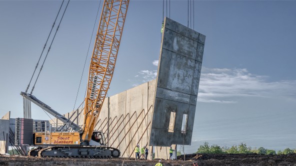 Liebherr crawler crane precisely hoisting a large precast concrete panel